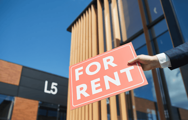 For rent sign outside a modern office building, illustrating strategies for finding tenants for commercial property.